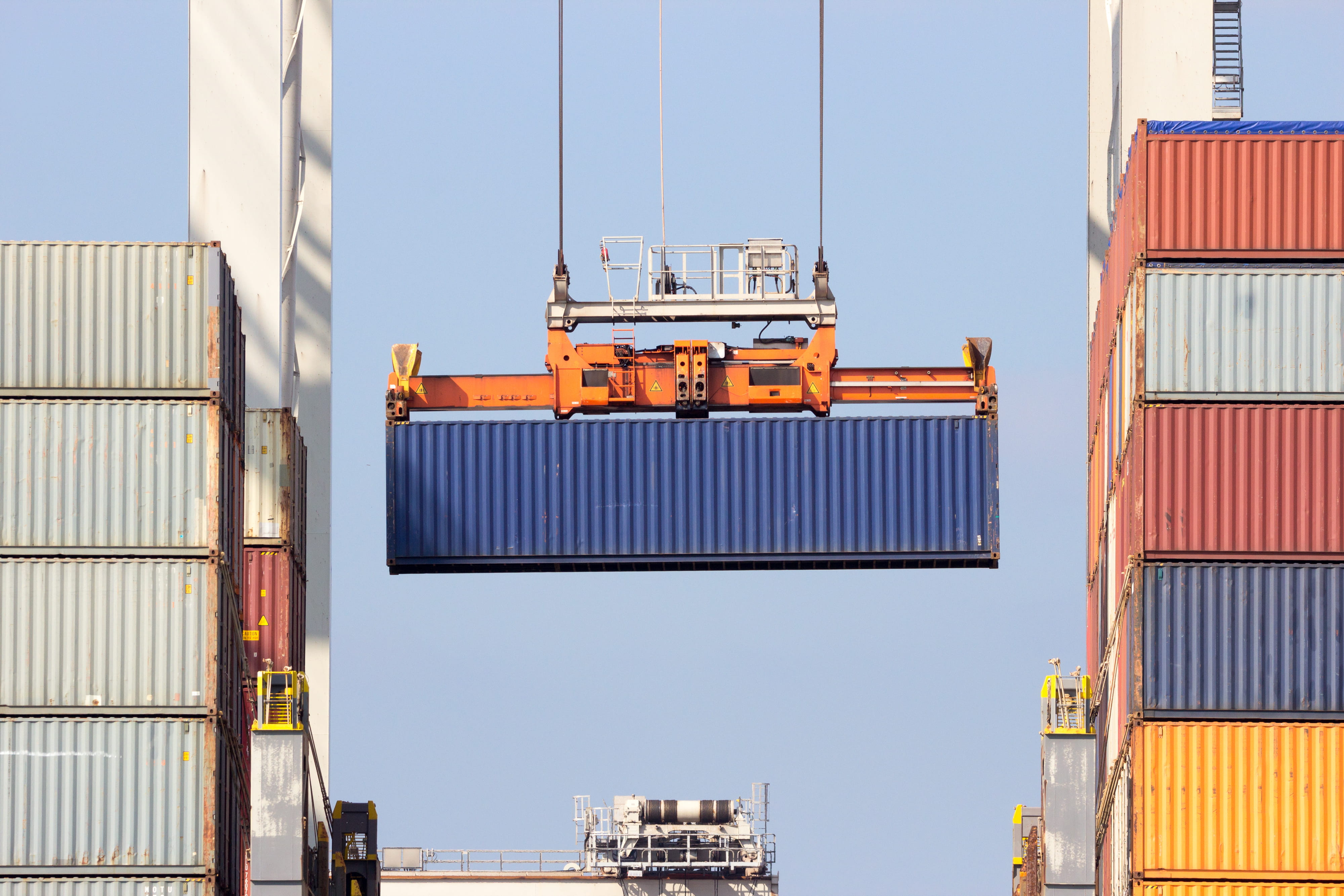 Container blir løftet med kran på havn hvor flere containere står i høyden